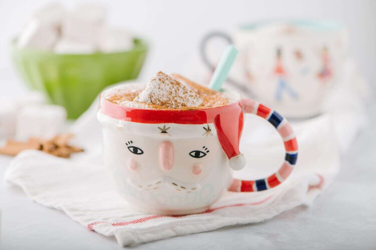 Creamy hot chocolate topped with marshmallows in a festive Santa mug for holiday baking.