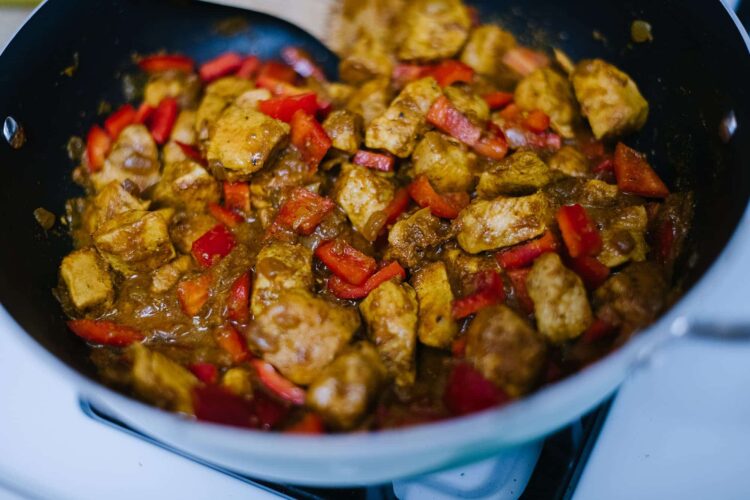 Savory chicken and red bell pepper stir-fry cooking in a skillet.