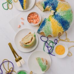 Festive Mardi Gras King Cake with colorful sugar sprinkles and beads for celebration.