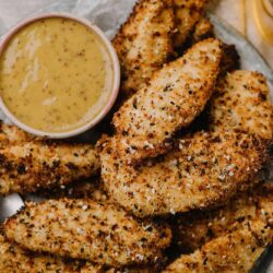 Crispy baked chicken tenders with seasoned breadcrumb coating and a side of honey mustard dip.