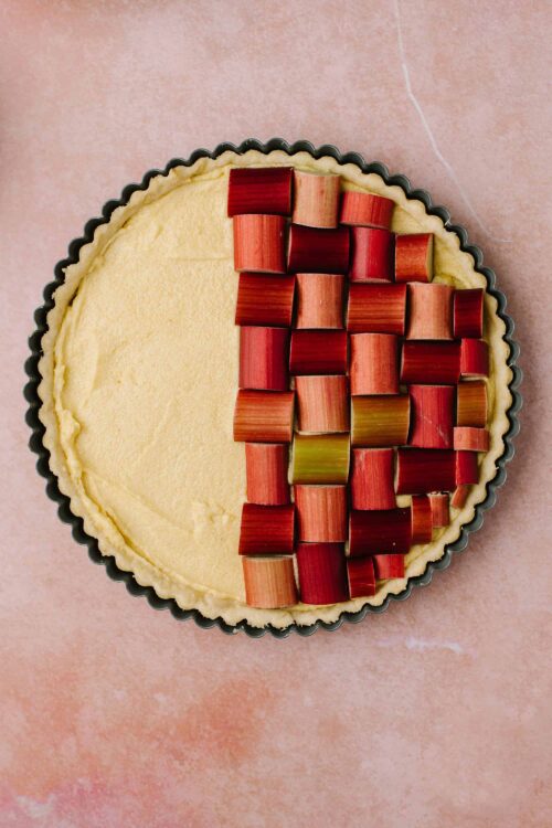 Rhubarb tart prepped with fresh rhubarb slices on a pie crust.