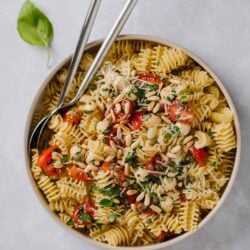 Creamy pasta salad with cherry tomatoes, basil, mozzarella, and pine nuts. Perfect for summer or family gatherings.