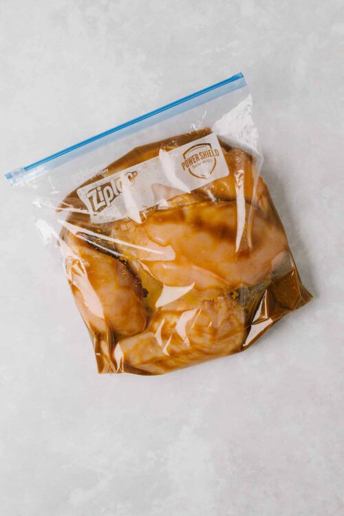 Vacuum-sealed marinated chicken breasts in a Ziploc bag for grilling or baking.