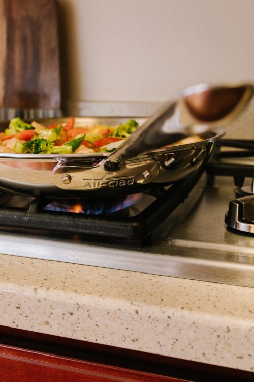 Steaming vegetables on a stovetop in a stainless steel pan.