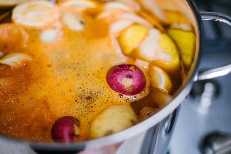 Boiling fruit cider with apples and radishes in a cooking pot.