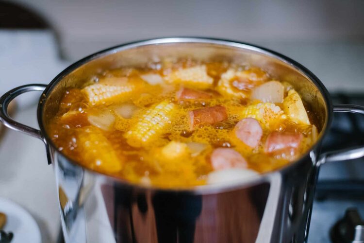 Savory sausage and corn chowder cooking in a stainless steel pot, hearty and comforting soup, popular winter meal.