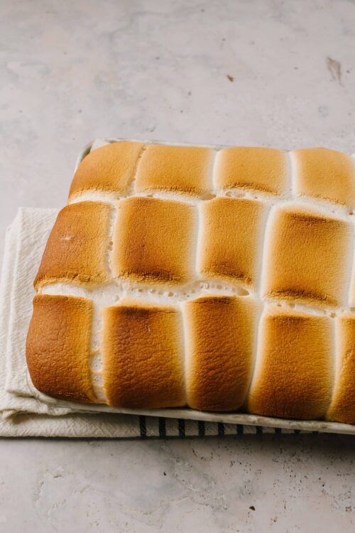 Fluffy toasted marshmallows on a baking sheet with graham crackers and chocolate, ready for s'mores.