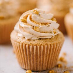 Golden cupcake with vanilla frosting and gold star sprinkles for Christmas or birthday celebrations.