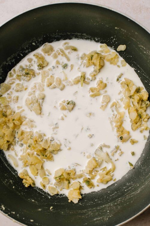 Creamy dessert mixture with chopped pecans in a skillet, ready for baking.