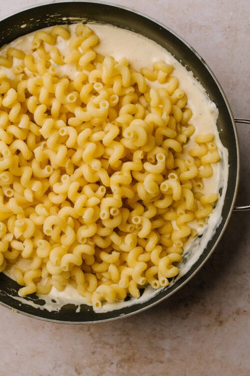 Creamy pasta with cheese and butter in a black skillet, ready for serving. Perfect comfort food recipe, easy to make at home.