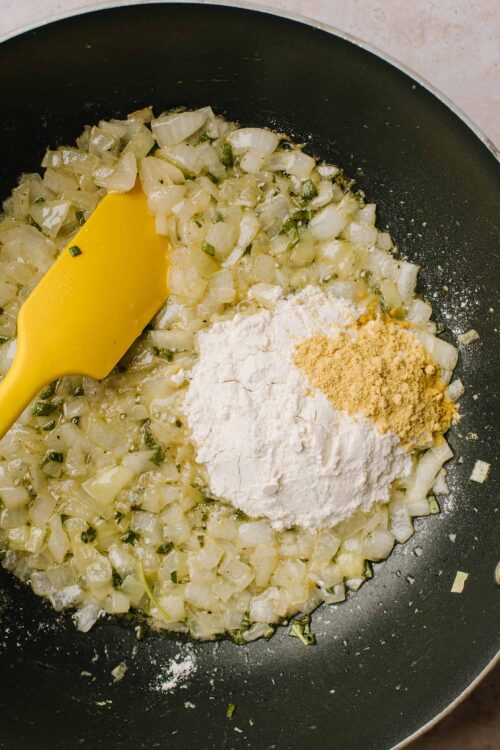 Sautéing onions and garlic with flour and spices in a frying pan for cooking or baking.