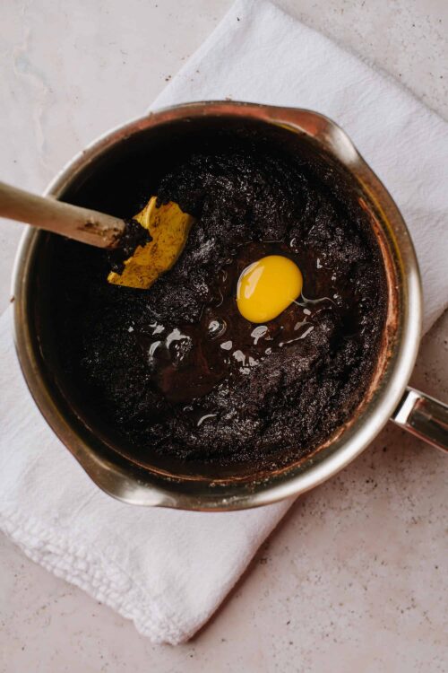 Rich chocolate batter with a raw egg in a mixing bowl, ready for baking.