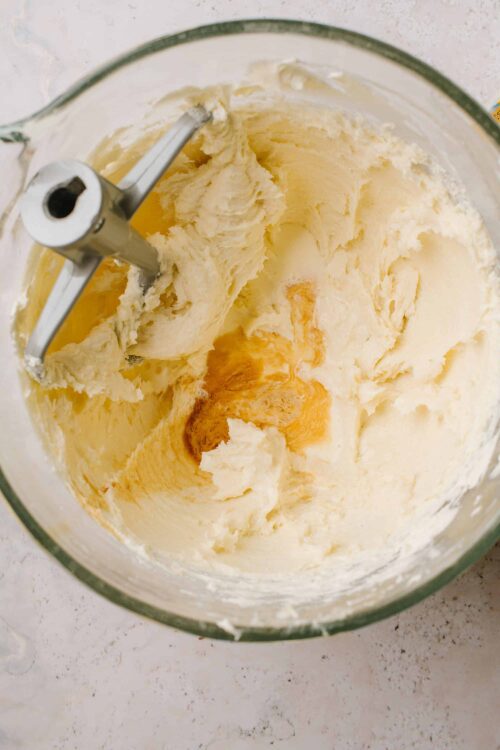 Creamy homemade vanilla buttercream frosting in a glass mixing bowl with a stand mixer attachment.