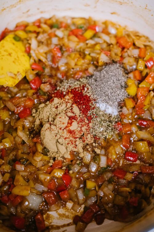 Seasoned sautéed vegetables in a skillet with spices and herbs for flavorful cooking.