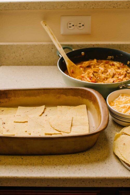 Shredded chicken and tortillas for homemade chicken tacos on a kitchen counter.