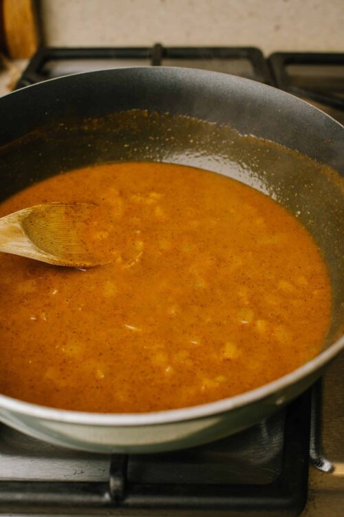 Creamy tomato soup in a black pot, simmering on stove.