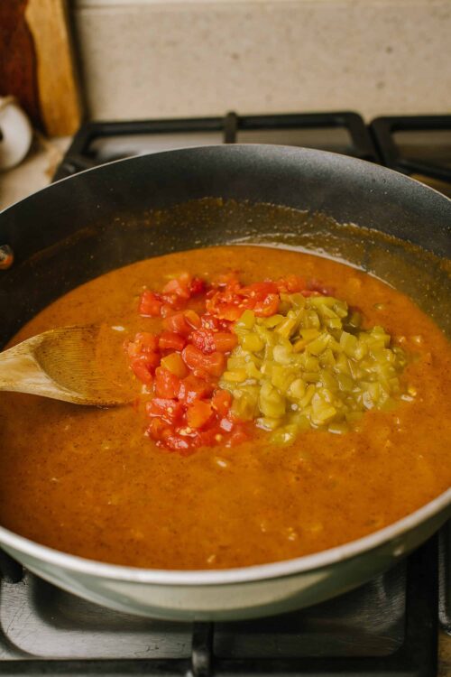 Creamy tomato and pickle relish soup cooking in a black skillet on stovetop.