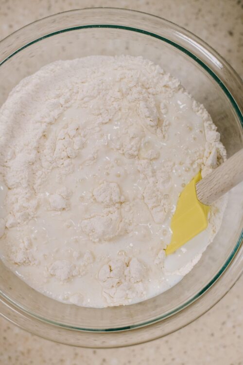 Flour and milk mixture in a glass mixing bowl for baking bread or cake.