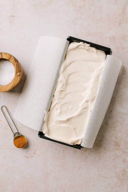 Creamy homemade ice cream in a black container with parchment paper, ready to freeze.