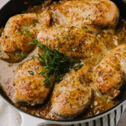 Juicy baked chicken thighs with herbs and garlic in a skillet.