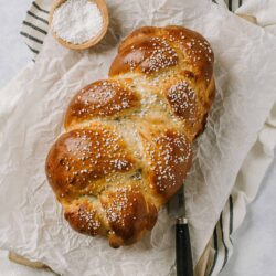 Fluffy, golden brioche bread sprinkled with pearl sugar on parchment paper.