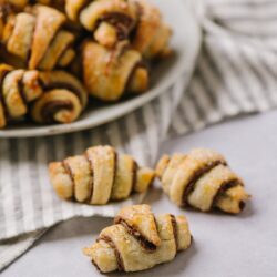 Delicious homemade croissant cookies with chocolate filling on a white surface.