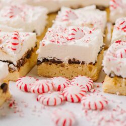 Sweet peppermint bark dessert squares with candy canes and whipped cream topping.