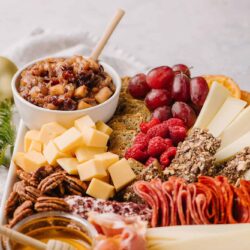 Cream cheese and fruit charcuterie board with grapes, raspberries, cheeses, and nuts for entertaining.