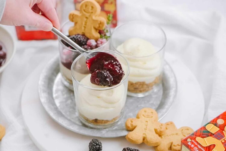 Velvet cheesecake trifles with berry compote in individual glasses on a silver tray.
