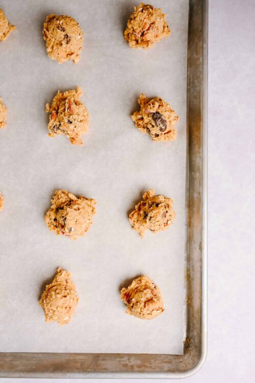 Cookie dough balls with chocolate chips on baking sheet.