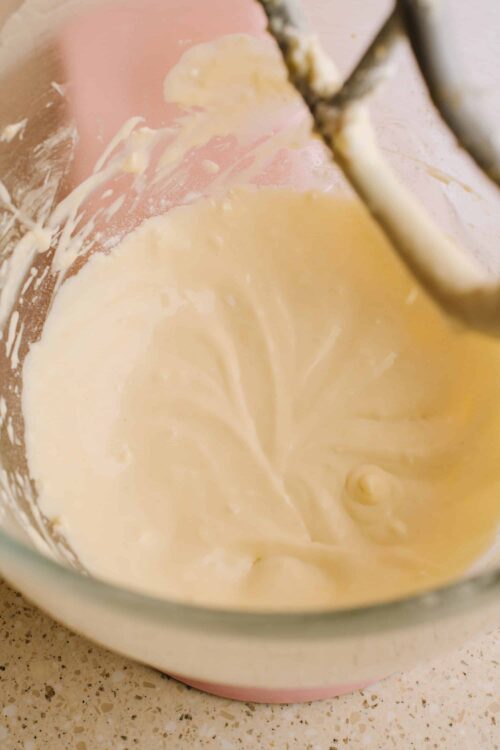 Creamy cake batter in a glass mixing bowl with beaters, ready for baking.