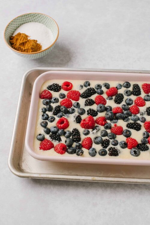 Fresh mixed berries topping creamy dessert in a baking dish.