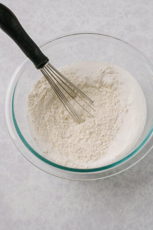 Fine white flour in a mixing bowl with a whisk for baking.
