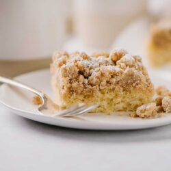 Butter crumb cake with a crumble topping on a white plate.