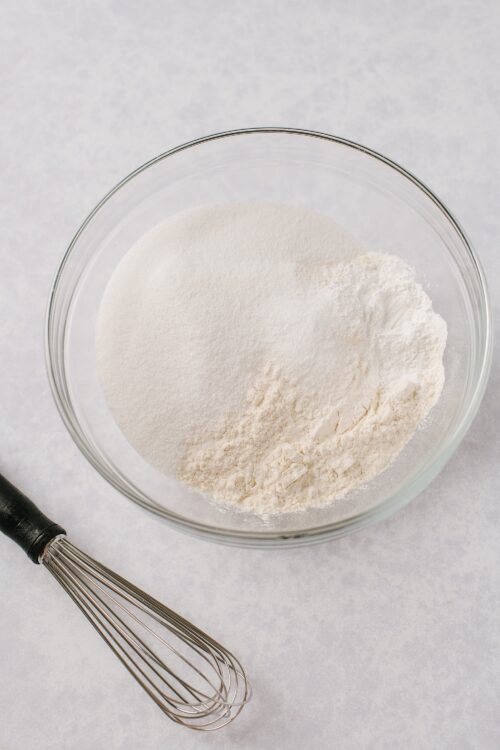 Fine white flour in a glass bowl with a whisk, ingredient for baking or cooking.