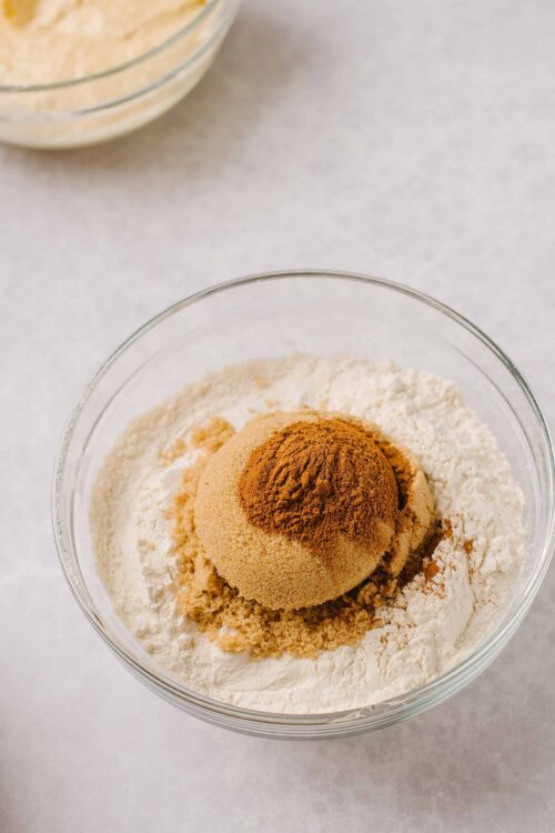 Flour, cinnamon, brown sugar, and vanilla extract in a mixing bowl for baking.