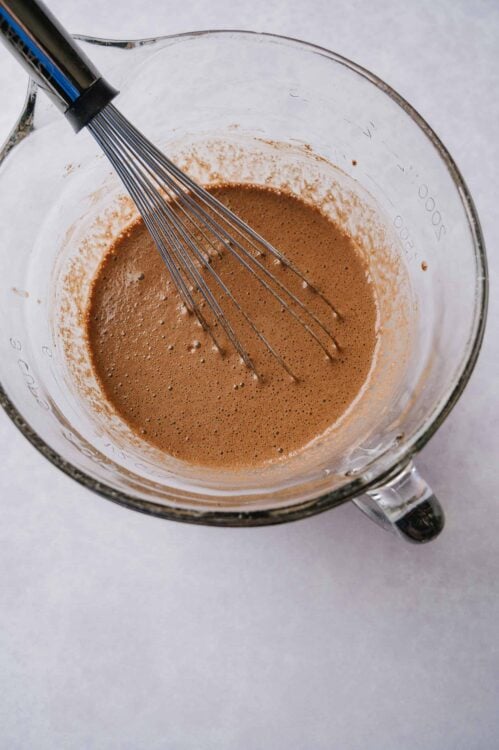 Smooth chocolate batter in glass mixing pitcher with whisk.