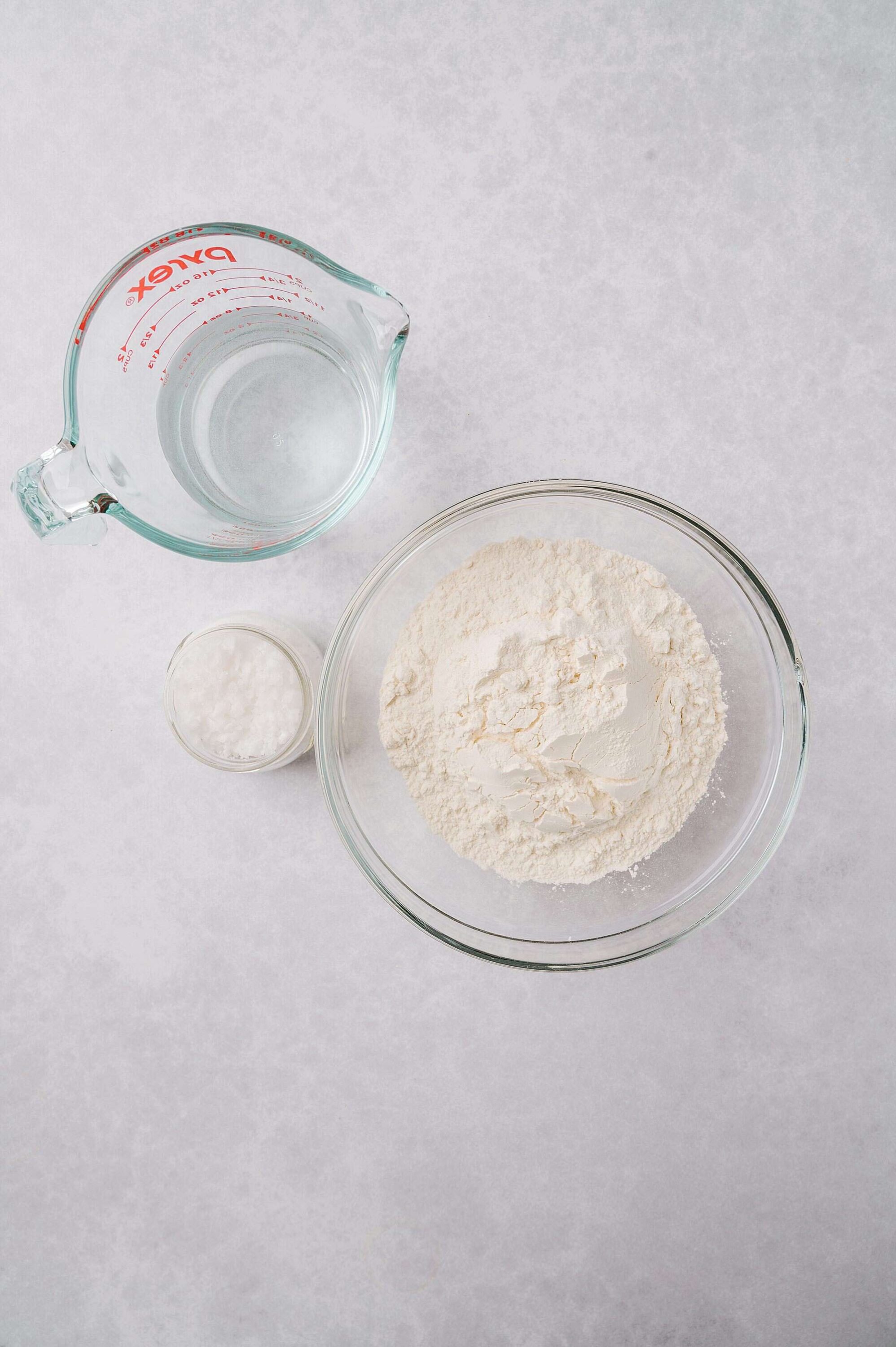 Flour and water ingredients for baking on a light gray background.