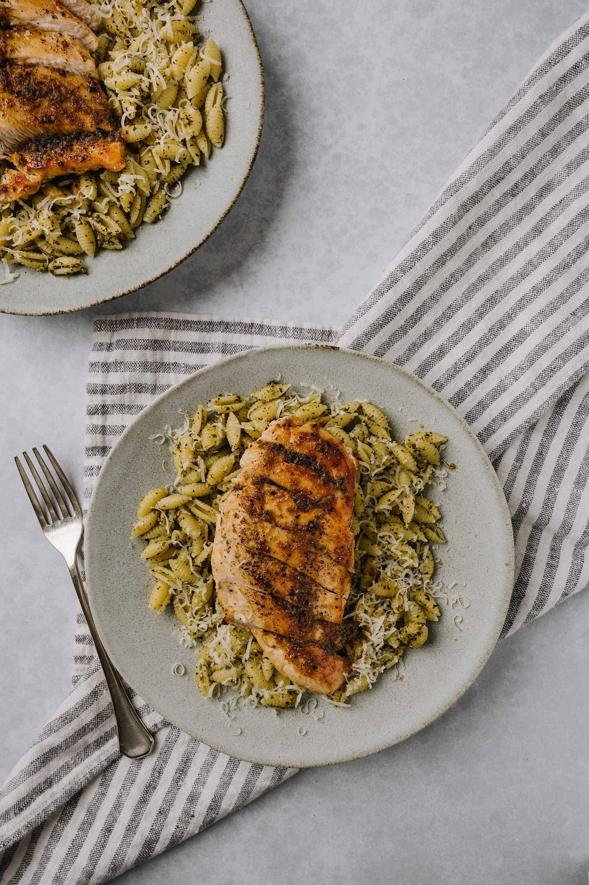 Creamy pesto pasta with grilled chicken, grated cheese, and fresh herbs. Easy and delicious weeknight dinner idea.