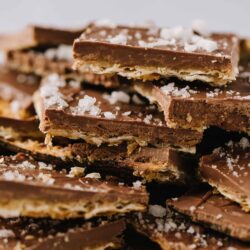 Chocolate almond toffee bars with sea salt, stacked and broken into pieces, close-up.