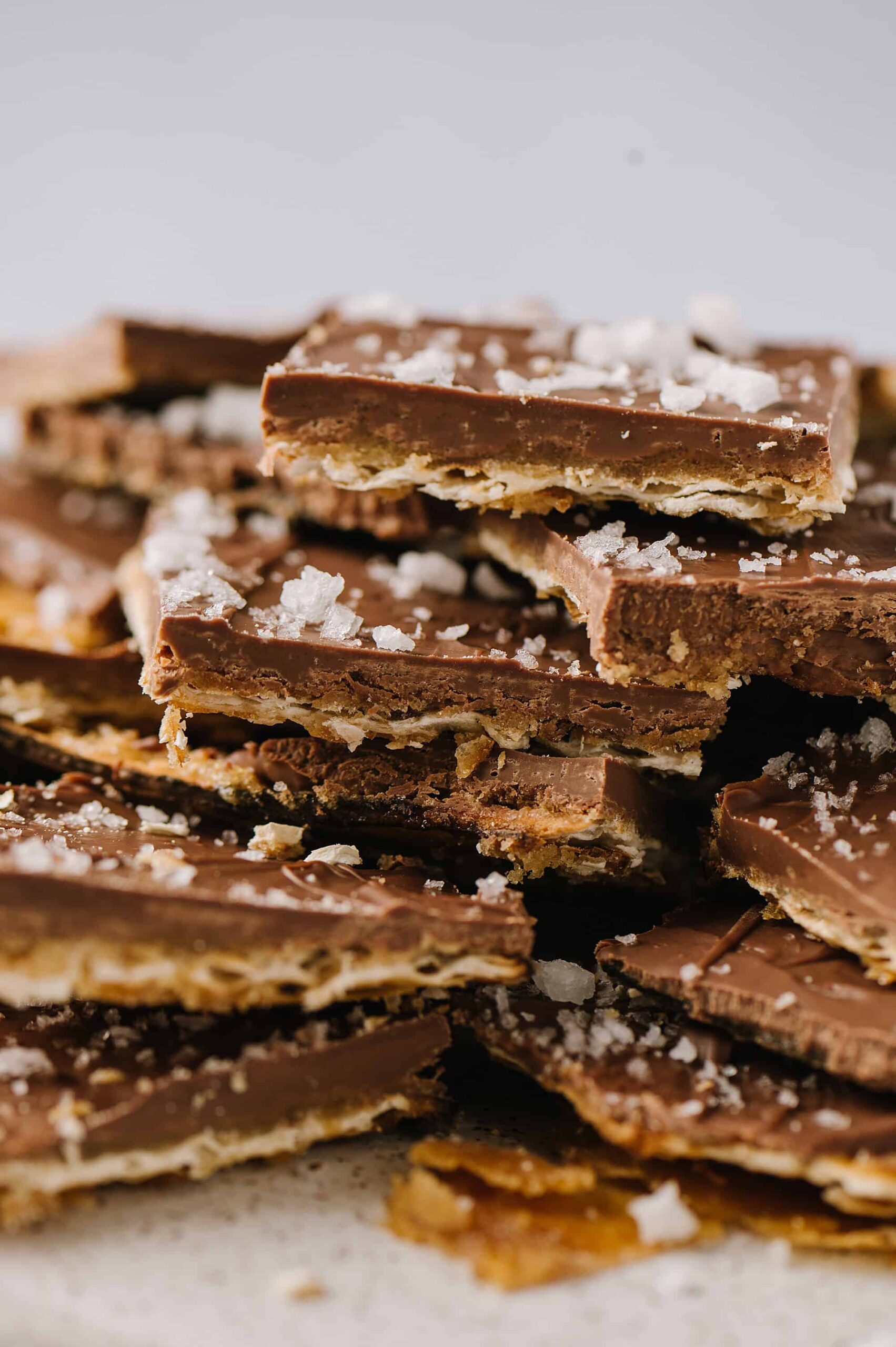 Chocolate almond toffee bars with sea salt, stacked and broken into pieces, close-up.