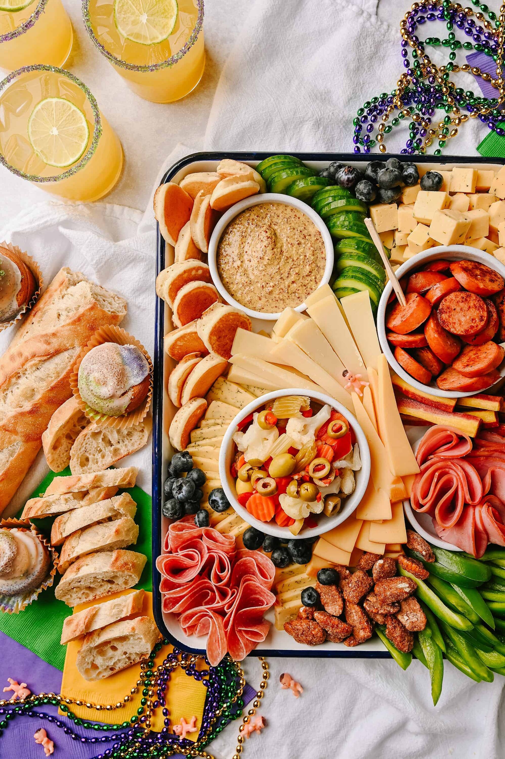 Cheese and charcuterie platter with assorted meats, cheeses, crackers, fruits, and dips for party snacking.