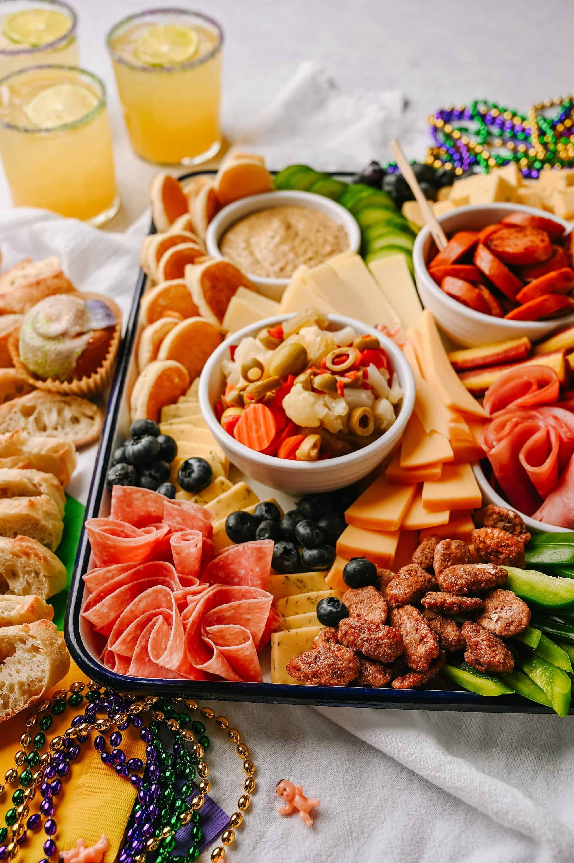 Assorted charcuterie platter with cheeses, cured meats, fresh vegetables, and condiments for entertaining.