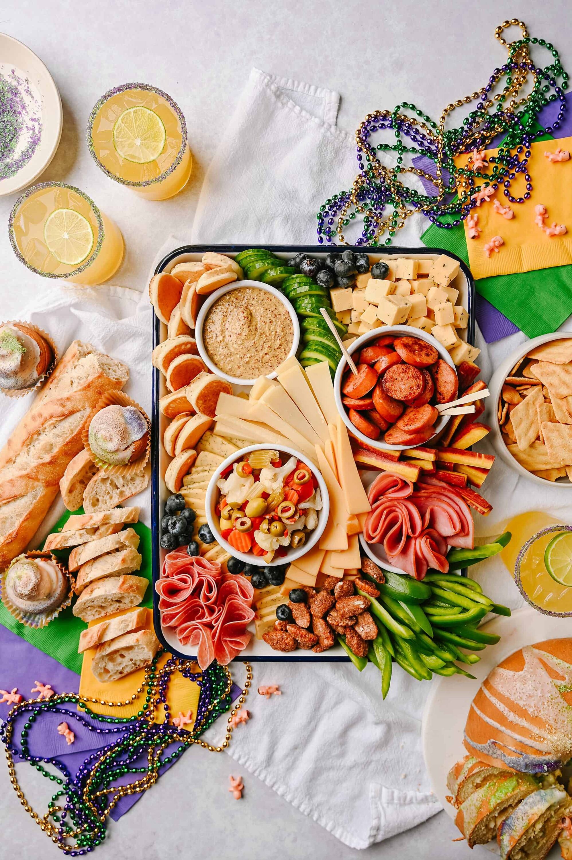 Colorful New Year's Eve cheese and charcuterie board with meats, cheeses, fruits, and dips.