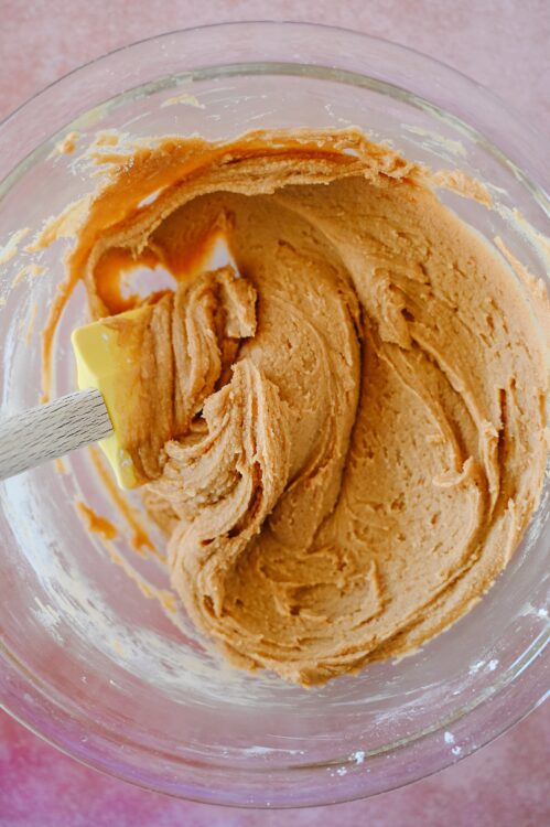 Creamy peanut butter mixture in a glass bowl for baking recipes.