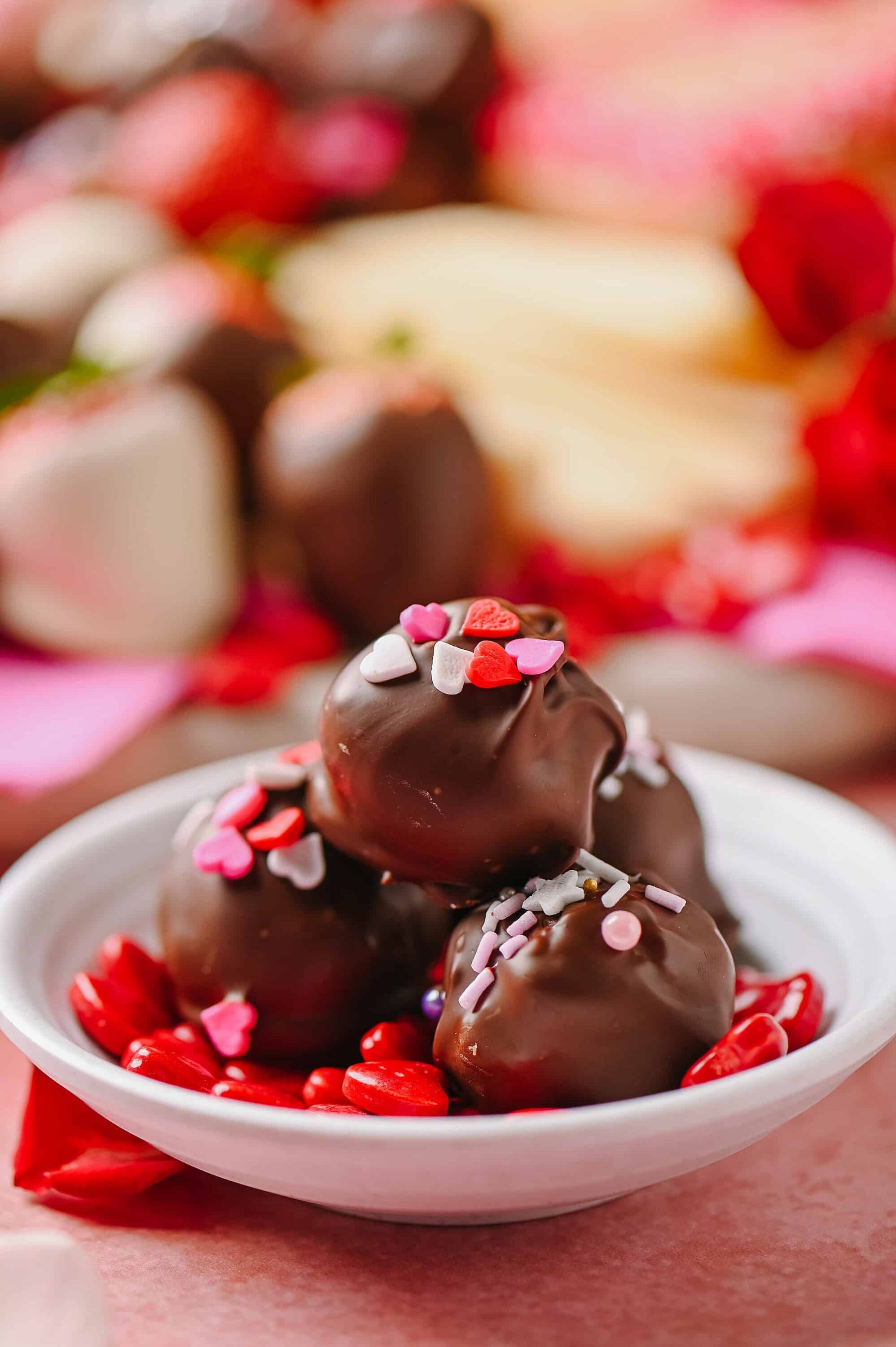 Rich chocolate truffles topped with colorful heart sprinkles and served on a white dish. Perfect for Valentine's Day or romantic celebrations.