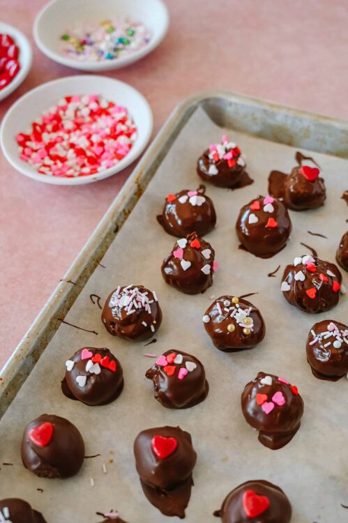 Chocolate truffles with heart-shaped sprinkles on top, Valentine's Day treat, homemade dessert, decorated bite-sized chocolates.