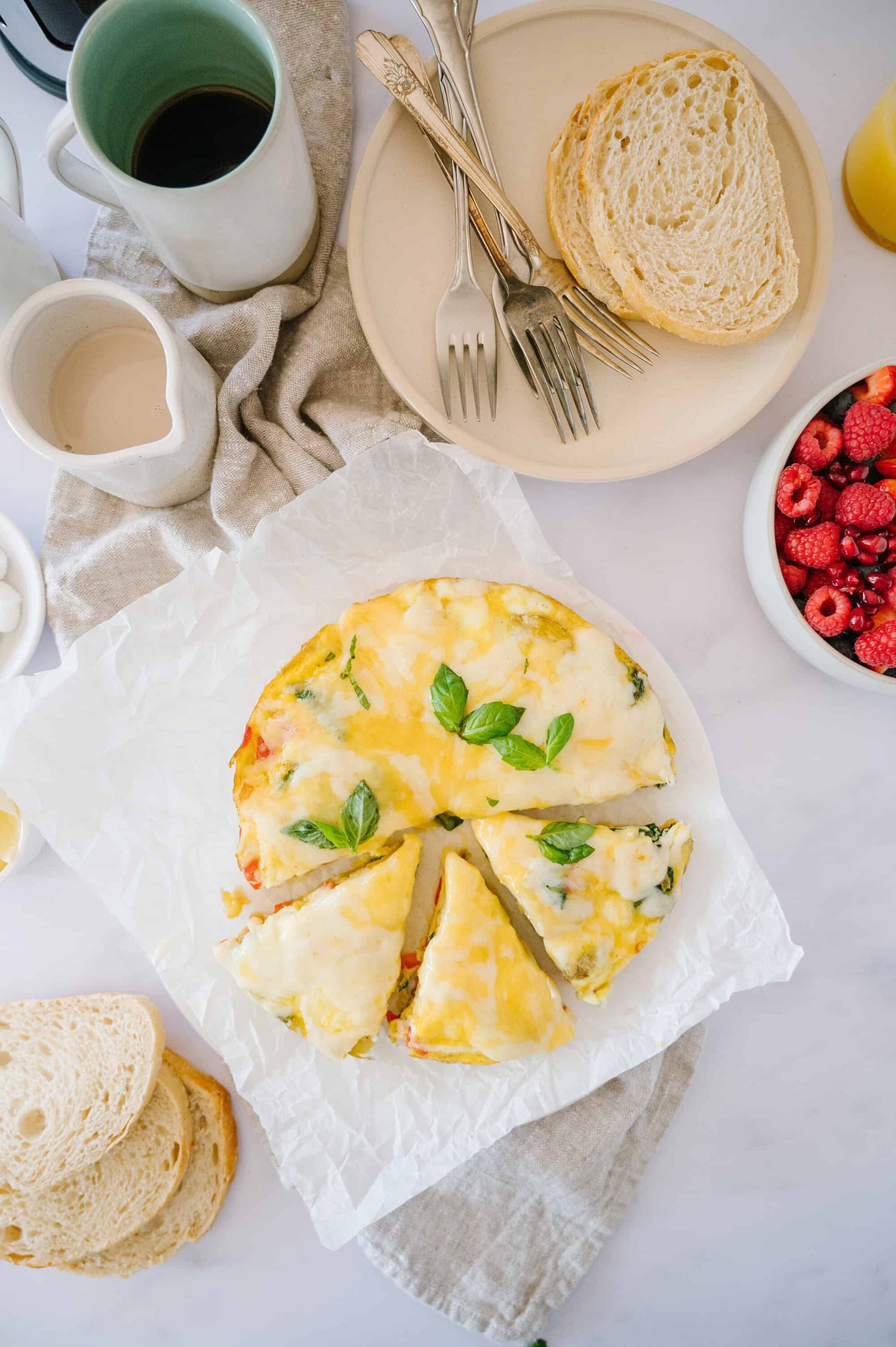 Fluffy cheesy spinach frittata served with bread and fresh berries for breakfast or brunch.