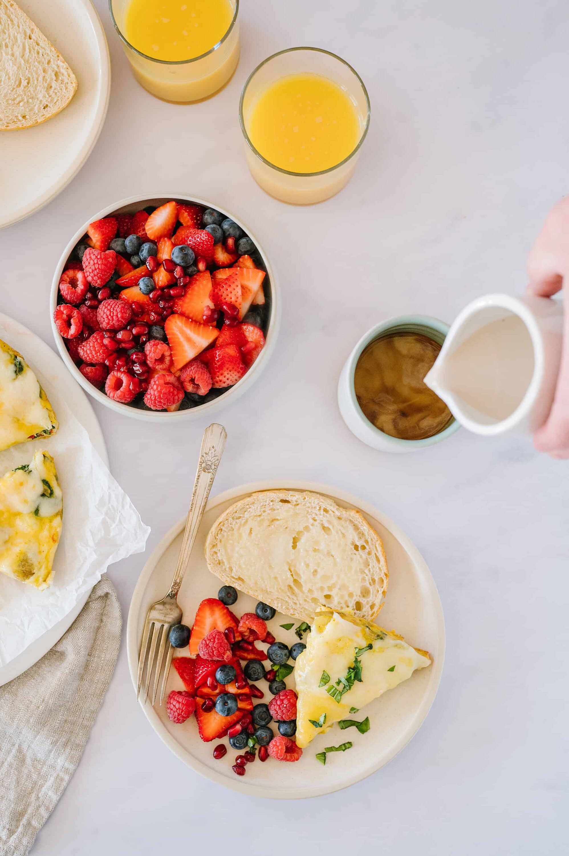 Fresh fruit salad with berries and sliced strawberries, served with breakfast bread and an omelette. Perfect for a healthy morning meal.