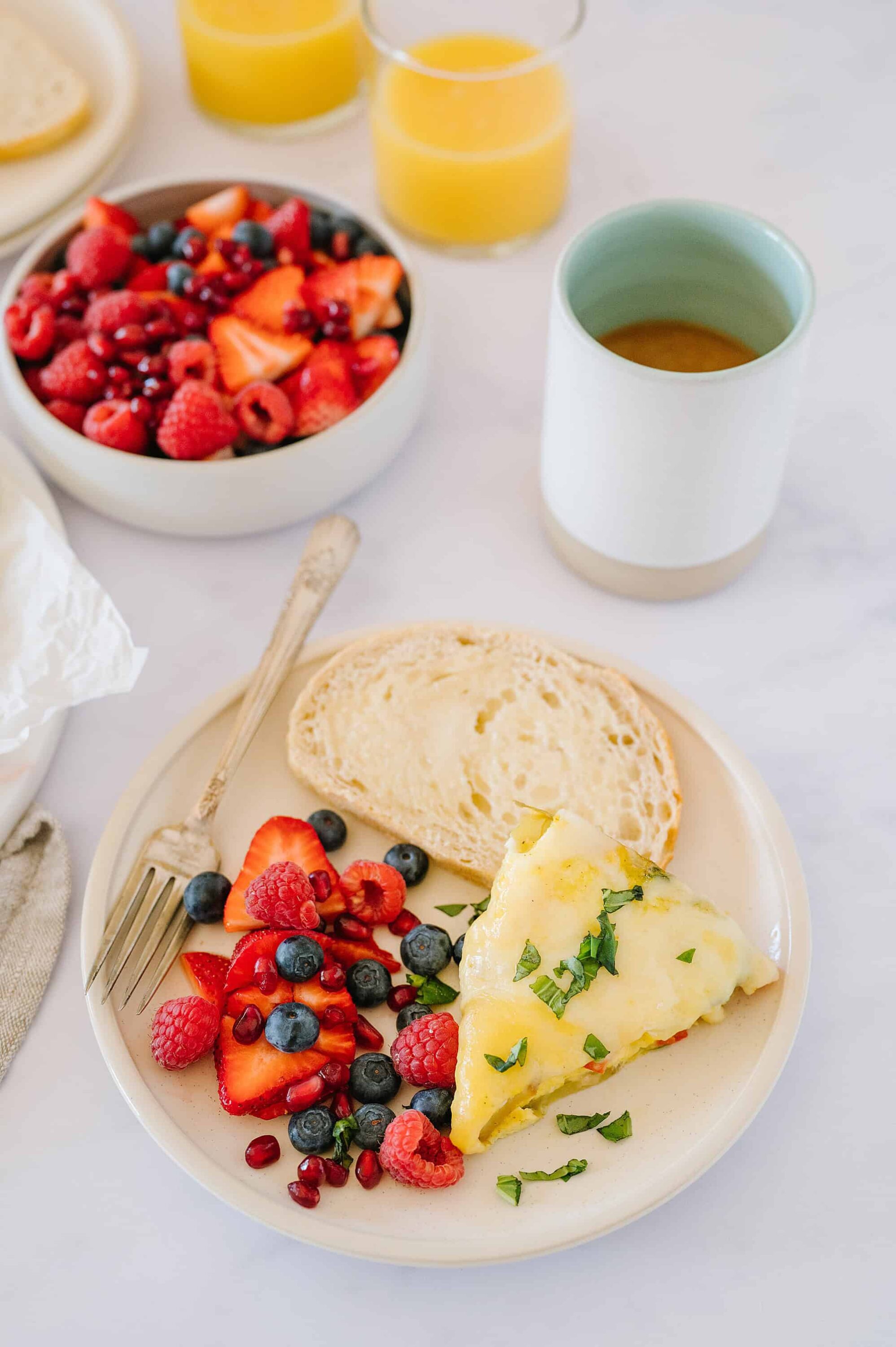 Fresh fruit and vegetable omelette with berries and bread for breakfast.